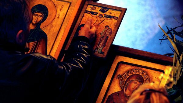 A man touches an icon with the crucifixion of Jesus Christ on Good Friday at St. Petka Orthodox church in Skopje, Macedonia - Sputnik Moldova-România