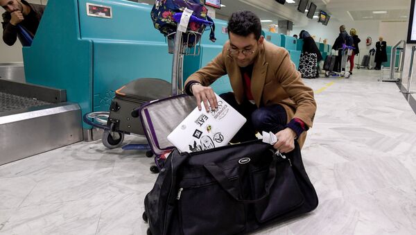 A Libyan traveller packs his laptop in his suitcase before boarding his flight for London at Tunis-Carthage International Airport on March 25, 2017 - Sputnik Moldova
