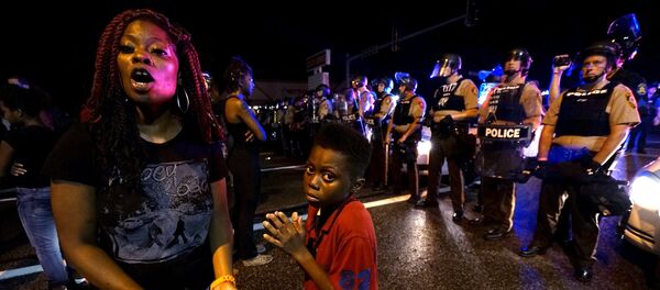 Amarion Allen, 11-years-old (C), and his mother Amima stand in front of a police line shortly before shots were fired in a police-officer involved shooting in Ferguson, Missouri August 9, 2015. - Sputnik Moldova