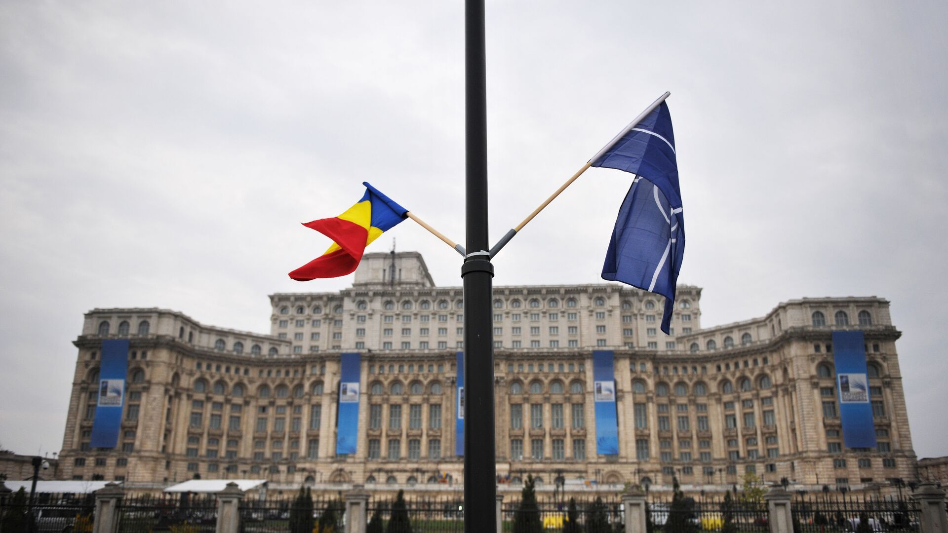 File photo of the Romanian and the NATO flag flutter in the wind in front of the Parliament Palace, the second largest building in the world after the Pentagon, in Bucharest on April 1, 2008 on the eve of the start of the NATO summit taking place form April 2 to 4 - Sputnik Moldova-România, 1920, 24.05.2022