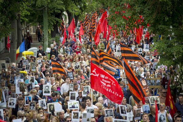 Копии Знамени Победы и флаги цветов Георгиевской ленты над маршем в честь Дня Победы - Sputnik Молдова