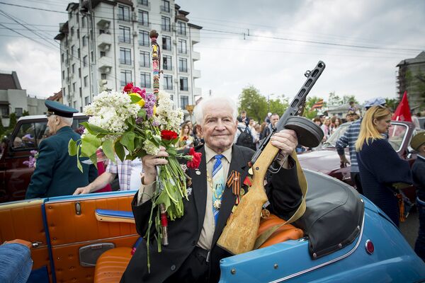 Ветеран Великой Отечественной войны на пассажирском сидении ретро-автомобиля держит в руке автомат - Sputnik Молдова