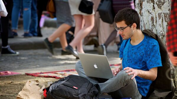 Молодой человек работает за ноутбуком, сидя на земле в парке. Хипстерский рынок - Sputnik Молдова