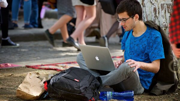 Молодой человек работает за ноутбуком, сидя на земле в парке. Хипстерский рынок - Sputnik Moldova-România