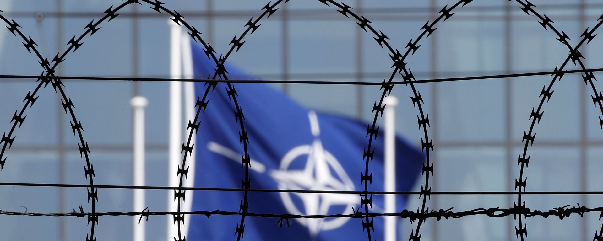 The NATO flag is seen through barbed wire as it flies in front of the new NATO Headquarters in Brussels, Belgium May 24, 2017 - Sputnik Moldova-România, 1920, 25.02.2022