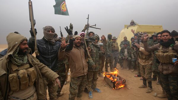 Iraqi Shiite fighters from the Hashed al-Shaabi (Popular Mobilisation) paramilitaries gesture to the camera as they warm up around a fire near the village of Tal Faris, south of Tal Afar, on November 30, 2016, during a broad offencive by Iraq forces to retake the city Mosul from jihadists of the Islamic State group - Sputnik Moldova-România