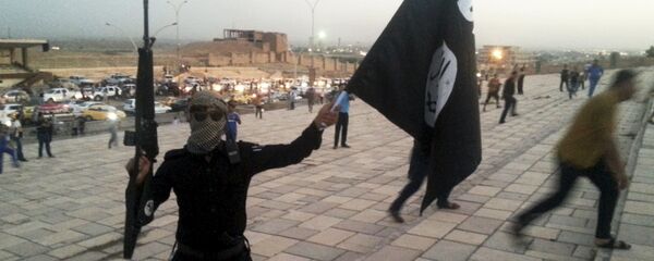 A fighter of Daesh holds an ISIL flag and a weapon on a street in the city of Mosul, Iraq, in this June 23, 2014. - Sputnik Moldova-România