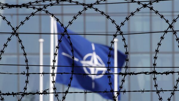 The NATO flag is seen through barbed wire as it flies in front of the new NATO Headquarters in Brussels, Belgium May 24, 2017 - Sputnik Moldova