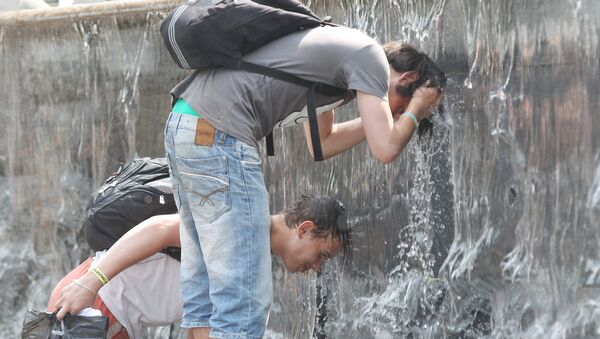 People cool down by placing their heads under running water from a fountain in Moscow. - Sputnik Moldova-România