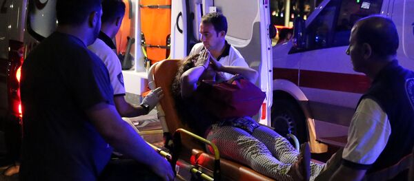 An injured woman covers her face as she is carried by paramedics into ambulance at Istanbul Ataturk airport, Turkey, following a blast June 28, 2016. - Sputnik Moldova-România