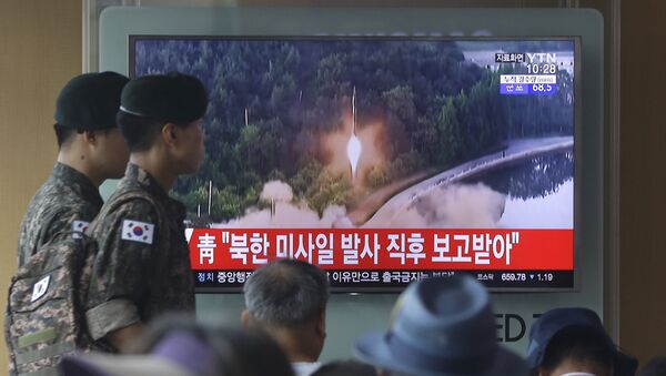 Army soldiers walk by a TV news program showing a file image of a missile being test-launched by North Korea at the Seoul Railway Station in Seoul, South Korea, Tuesday, July 4, 2017. - Sputnik Moldova-România