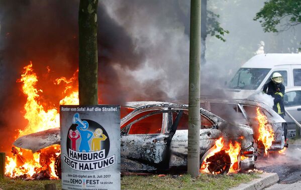 Пожарные сражаются с огнем на месте, где были подожжены несколько автомобилей во время акций протеста против саммита G20 в Гамбурге - Sputnik Молдова