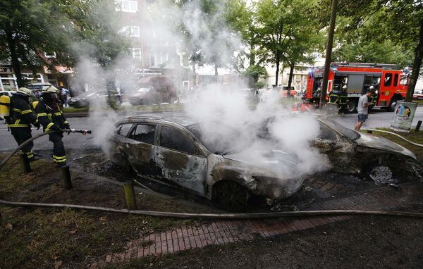 Пожарные работают на месте, где в результате беспорядков во время демонстраций против G20 в Гамбурге сгорели ряд автомобилей - Sputnik Молдова