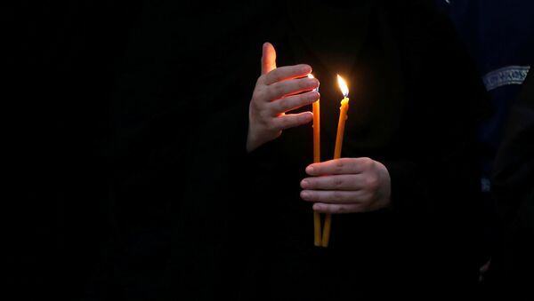 Монахиня держит зажженную свечу во время праздничной Пасхальной службы в Кафедральном соборе Святой Троицы Самеба - Sputnik Moldova-România
