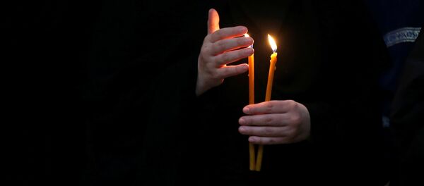 Монахиня держит зажженную свечу во время праздничной Пасхальной службы в Кафедральном соборе Святой Троицы Самеба - Sputnik Moldova