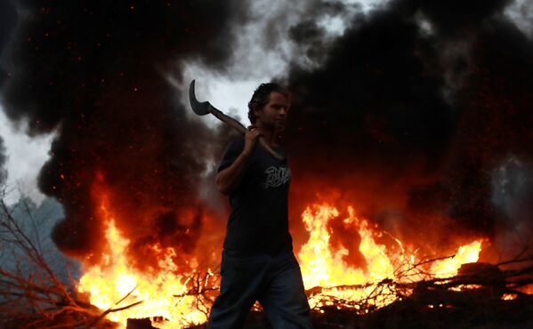 Член Бразильского движения бездомных рабочих идет по шоссе вдоль горящей баррикады во время протестов против предложения президента Мишеля Темера о реформировании системы социального обеспечения Бразилии - Sputnik Молдова