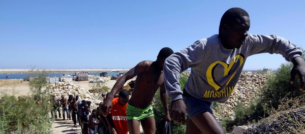 Спасенные мигранты идут на побережье Гараболи, к востоку от Триполи, Ливия  - Sputnik Moldova-România