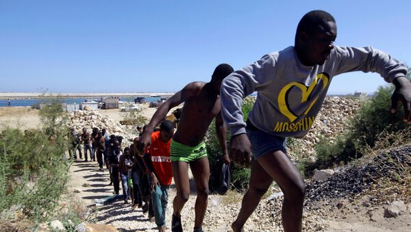 Спасенные мигранты идут на побережье Гараболи, к востоку от Триполи, Ливия  - Sputnik Moldova-România