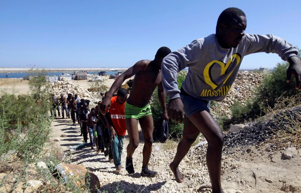 Спасенные мигранты идут по побережью Гараболи, к востоку от Триполи, Ливия - Sputnik Молдова