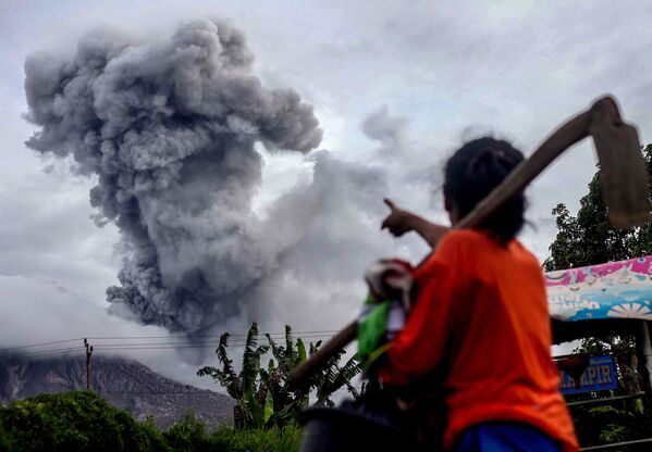 Житель деревни указывает на вулкан Синабунг, который извергает густой вулканический пепел, Северная Суматра - Sputnik Молдова