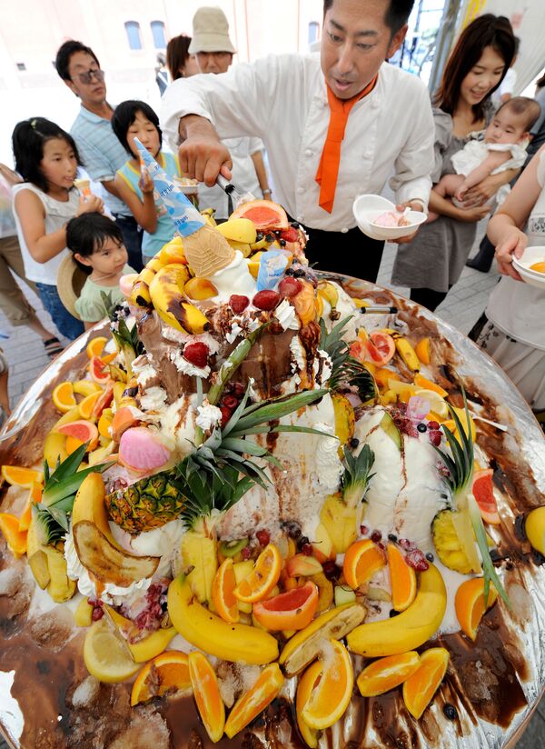 Повар нарезает 100-килограммовый торт-мороженое, украшенный фруктами, во время летнего фестиваля в Йокогаме, Япония - Sputnik Молдова