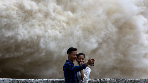 Пара фотографируется на фоне сброса воды на ГЭС Хоабинь во Вьетнаме после тайфуна - Sputnik Moldova-România