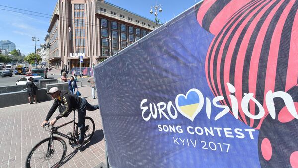 Человек едет на велосипеде мимо официального логотипа конкурса песни «Евровидение» в центре Киева - Sputnik Молдова