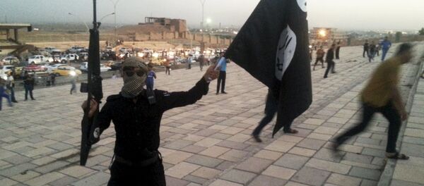 A fighter of Daesh holds an ISIL flag and a weapon on a street in the city of Mosul, Iraq, in this June 23, 2014. - Sputnik Moldova-România