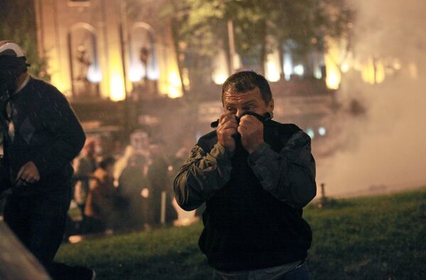 Участник акции протеста грузинской оппозиции закрывает лицо от слезоточивого газа во время беспорядков на проспекте Руставели в Тбилиси, 2011 год - Sputnik Молдова