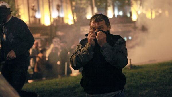 Участник акции протеста грузинской оппозиции закрывает лицо от слезоточивого газа во время беспорядков на проспекте Руставели в Тбилиси, 2011 год - Sputnik Молдова