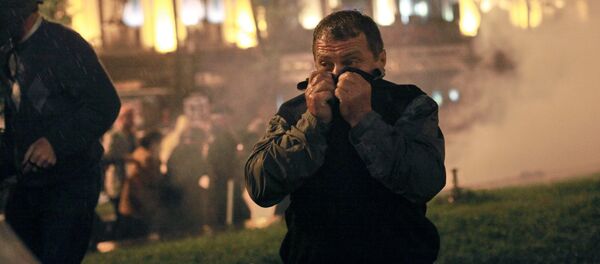 Участник акции протеста грузинской оппозиции закрывает лицо от слезоточивого газа во время беспорядков на проспекте Руставели в Тбилиси, 2011 год Участник акции протеста грузинской оппозиции закрывает лицо от слезоточивого газа во время беспорядков на проспекте Руставели в Тбилиси, 2011 год - Sputnik Молдова