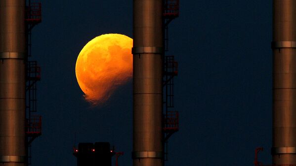 Восходящая луна во время частичного лунного затмения за трубами электростанции в Делимаре, недалеко от Мальты - Sputnik Молдова
