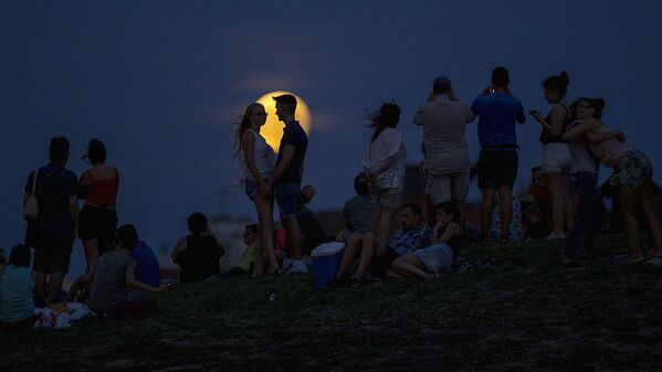 Люди наблюдают за восходящей луной во время частичного лунного затмения на вершине холма в парке Тио Пио в Мадриде - Sputnik Молдова