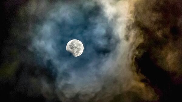 Луна, обрамленная пеплом от вулкана Маунт Синабунг, видна во время частичного лунного затмения в провинции Северная Суматра в Индонезии - Sputnik Молдова