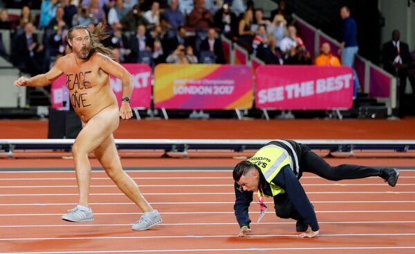 Охранник преследует стрикера, выбежавшего на трассу Лондонского стадиона во время чемпионата мира по легкой атлетике - Sputnik Молдова