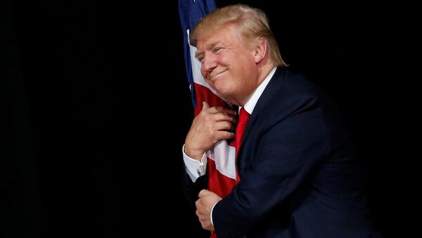 Donald Trump hugs a U.S. flag as he comes onstage to rally with supporters in Tampa, Florida, U.S. October 24, 2016 - Sputnik Moldova-România