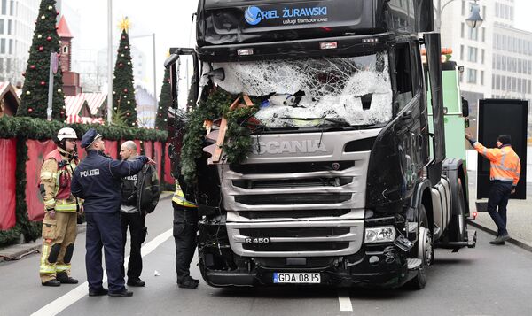 A policeman and firemen stand next to a truck on December 20, 2016 at the scene where it crashed into a Christmas market near the Kaiser-Wilhelm-Gedaechtniskirche (Kaiser Wilhelm Memorial Church) in Berlin A policeman and firemen stand next to a truck on December 20, 2016 at the scene where it crashed into a Christmas market near the Kaiser-Wilhelm-Gedaechtniskirche (Kaiser Wilhelm Memorial Church) in Berlin - Sputnik Moldova-România