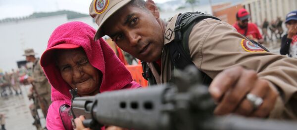 Полицейский Национальниых боливарианских вооруженных сил учит женщину использовать винтовку во время военных учений в Каракасе - Sputnik Молдова