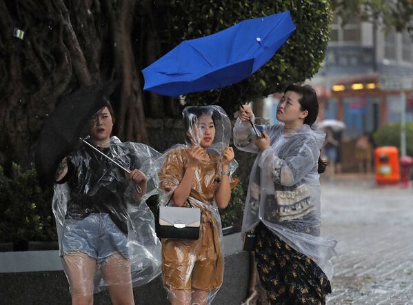 Девушки с зонтиками во время шторма в Гонконге - Sputnik Молдова