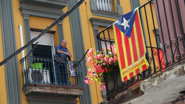 Мужчина развешивает одежду на балконе на севере Барселоны, на фоне флага Каталонии - Sputnik Молдова
