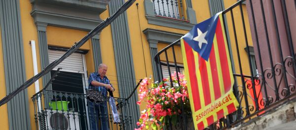 Мужчина развешивает одежду на балконе на севере Барселоны, на фоне флага Каталонии - Sputnik Молдова