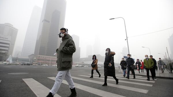A man wearing a respiratory protection mask walks toward an office building during the smog after a red alert was issued for heavy air pollution in Beijing's central business district, China, December 21, 2016 - Sputnik Moldova-România