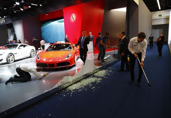 Люди подметают пол после того, как стеклянная доска врезалась в выставочный стенд Ferrari на Международном автомобильном салоне во Франкфурте, Германия - Sputnik Молдова