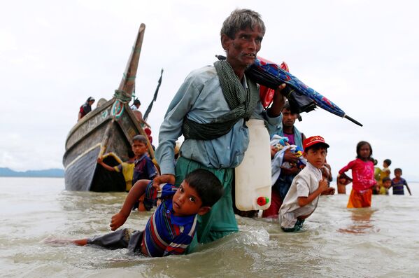 Мужчина из народности рохинджа вытаскивает ребенка из воды после пересечения границы Бангладеш через Бенгальский залив - Sputnik Молдова