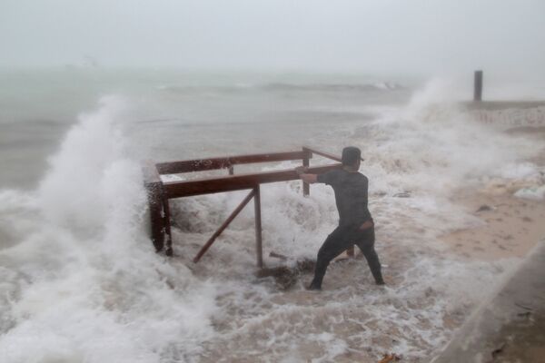 Мужчина пытается достать стол из океана, который унесло из ресторана во время урагана Мария в Пунта-Кана, Доминикана - Sputnik Молдова