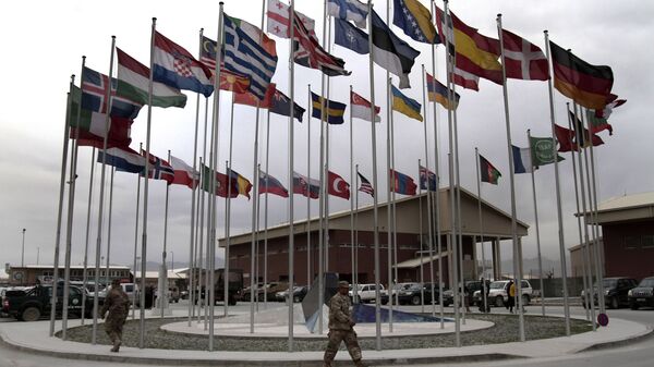 NATO Soldiers walk under country member flags at a NATO base at Kabul International Airport in Kabul, Afghanistan - Sputnik Moldova