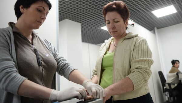 Иностранная гражданка (справа) проходит дактилоскопическую регистрацию, архивное фото - Sputnik Moldova