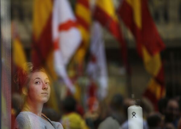 Женщина смотрит, как демонстранты собираются на митинг в защиту единства Испании в Барселоне - Sputnik Молдова