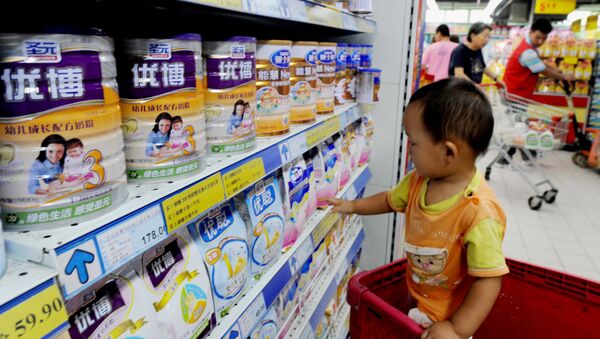 A Chinese baby plays beside tins of milk powder made by NASDAQ-listed Synutra (L-1) on sale at a supermarket in Beijing on August 9, 2010 - Sputnik Moldova-România