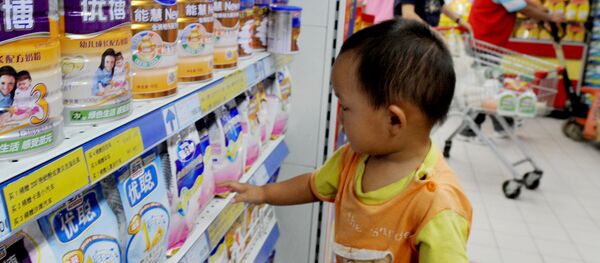 A Chinese baby plays beside tins of milk powder made by NASDAQ-listed Synutra (L-1) on sale at a supermarket in Beijing on August 9, 2010 - Sputnik Moldova-România